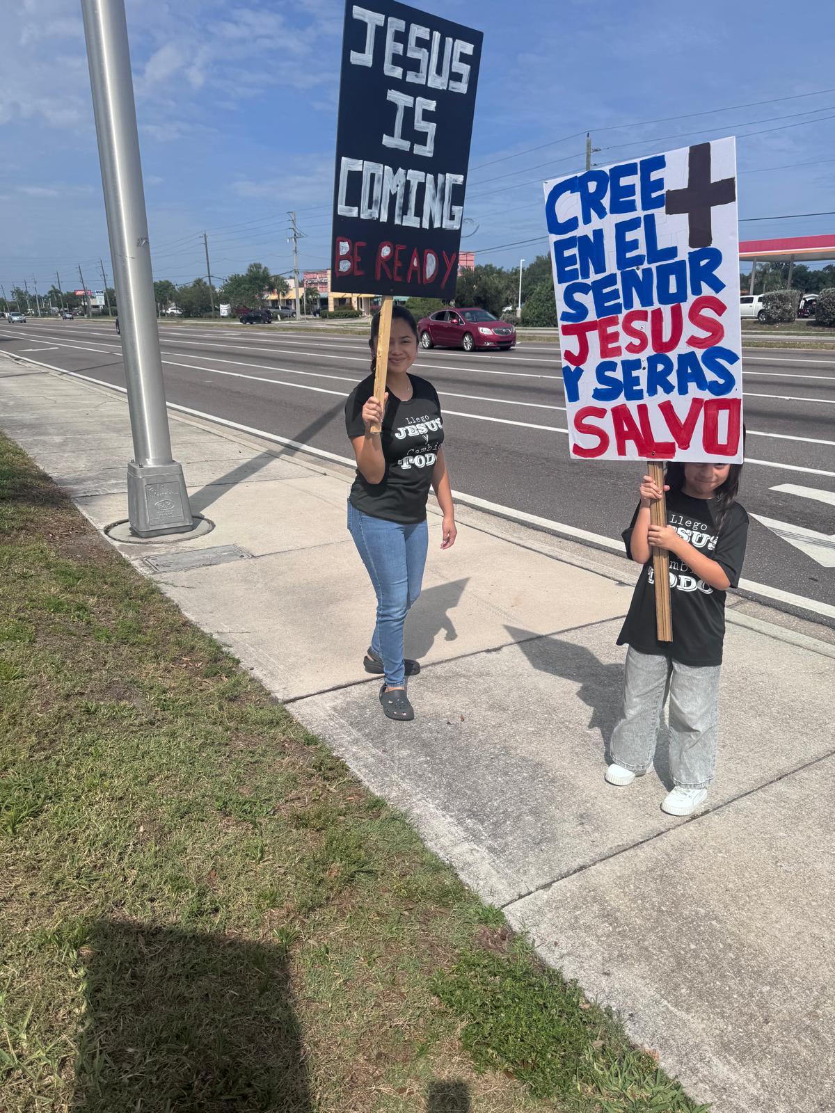 Madre e hija con carteles evangelizando en la calle